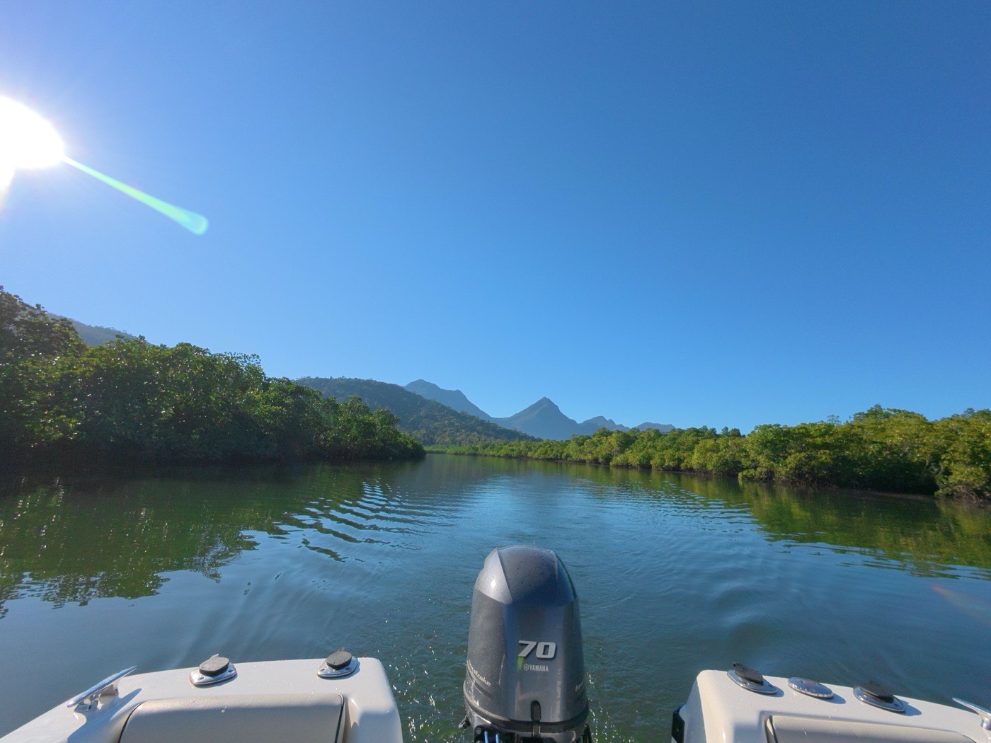 The bow of a survey boat on calm water, hills beyond