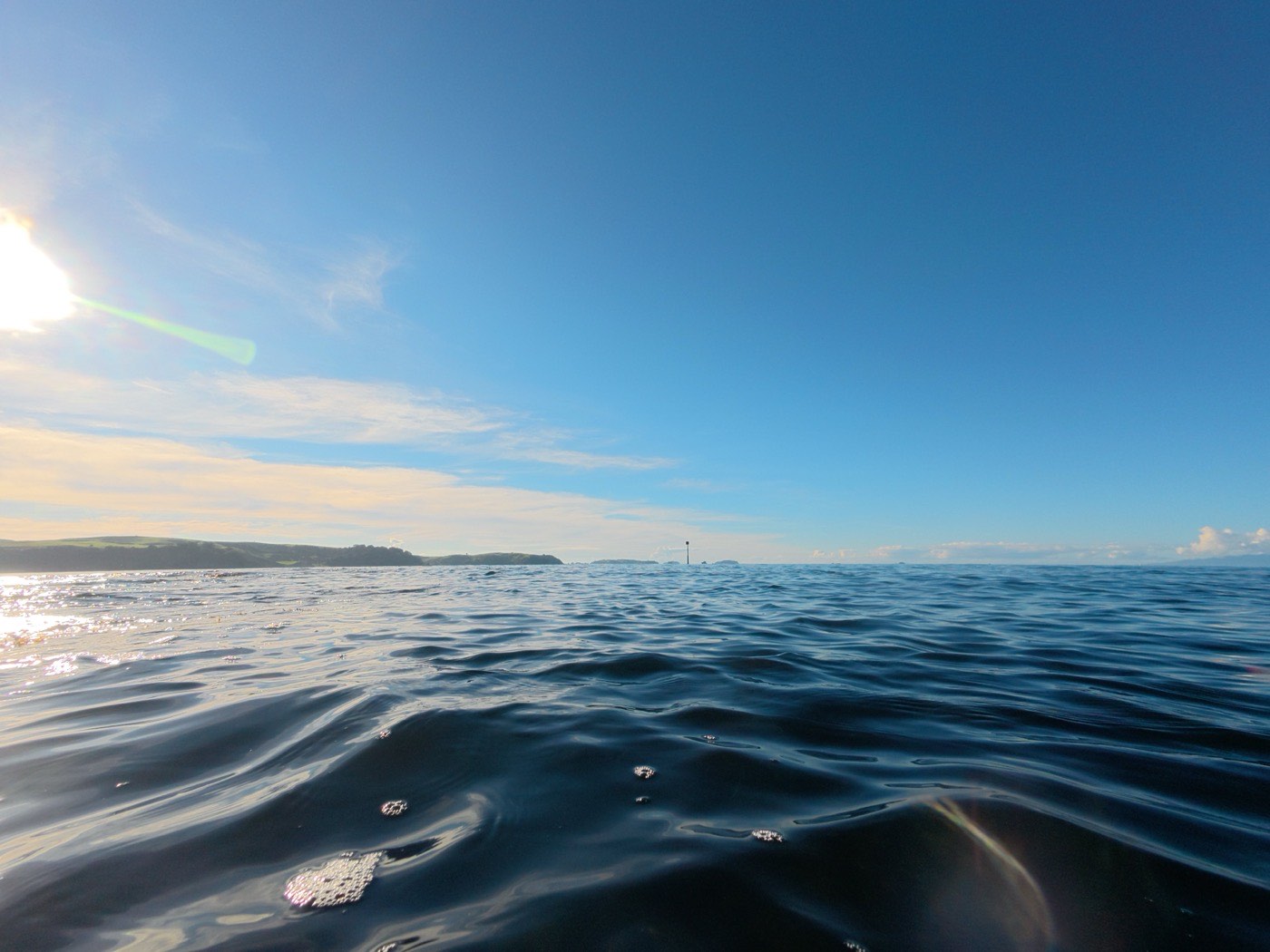Low sun over open water with a distant shoreline